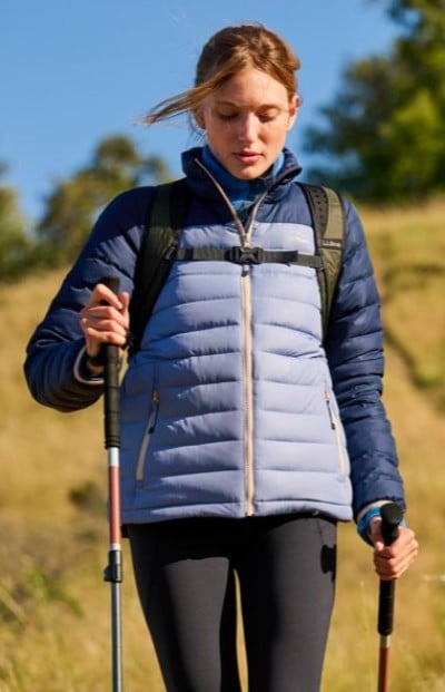Person hiking using trekking poles while wearing a blue colorblock jacket on a trail. 