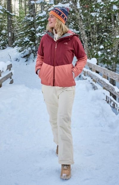 Person walking through a snowy forest wearing a pink color-block winter jacket.