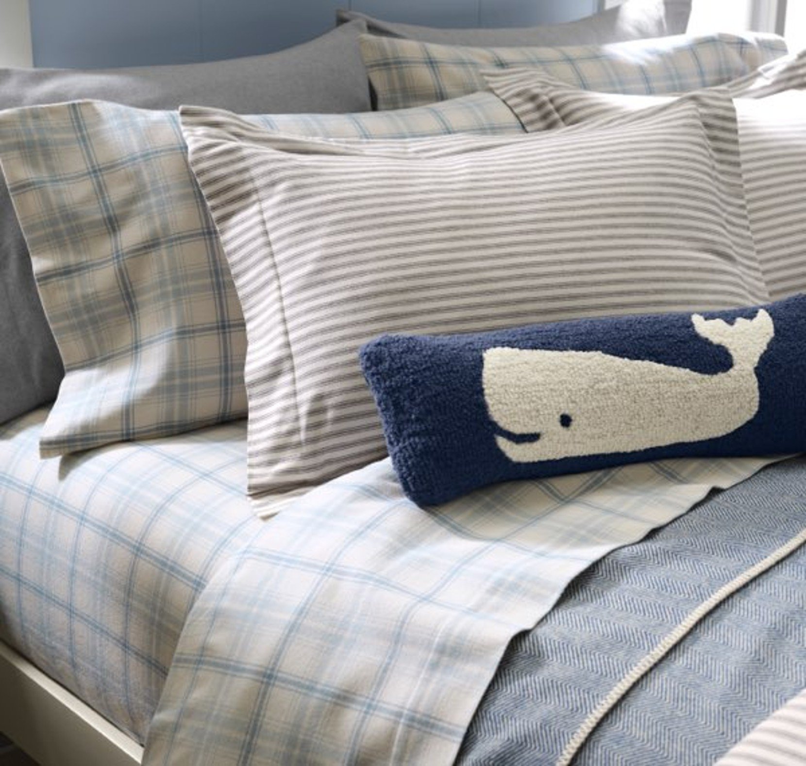 Plaid flannel bedding with pillows arranged on a bed in neutral tones.