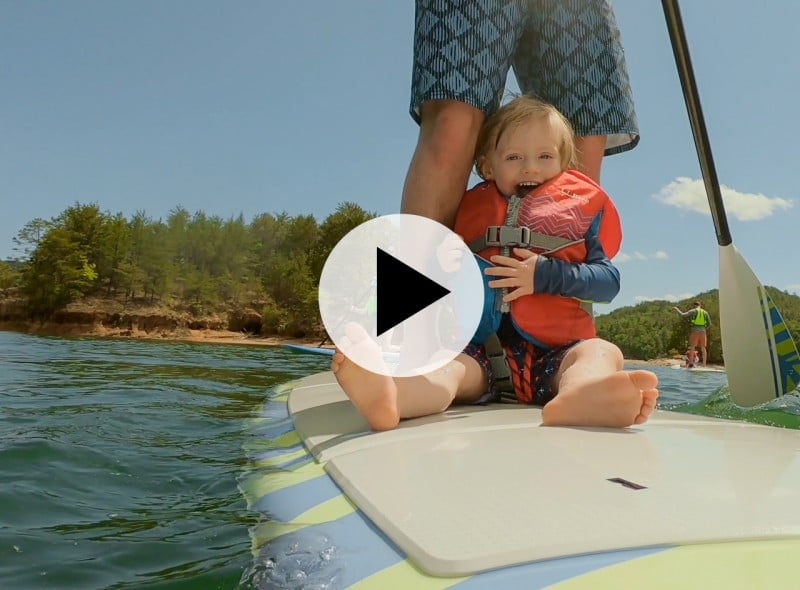 Baby sits on a paddleboard.