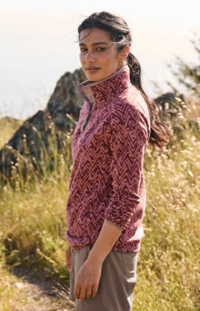 Person wearing a pink patterned fleece outdoors in tall grass.