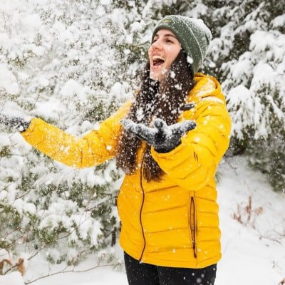 2 kids wearing L.L.Bean outerwear and pom hats outside in the snow.