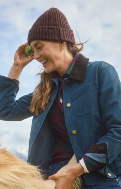 Person wearing a knit beanie and blue jacket outdoors on a windy day.