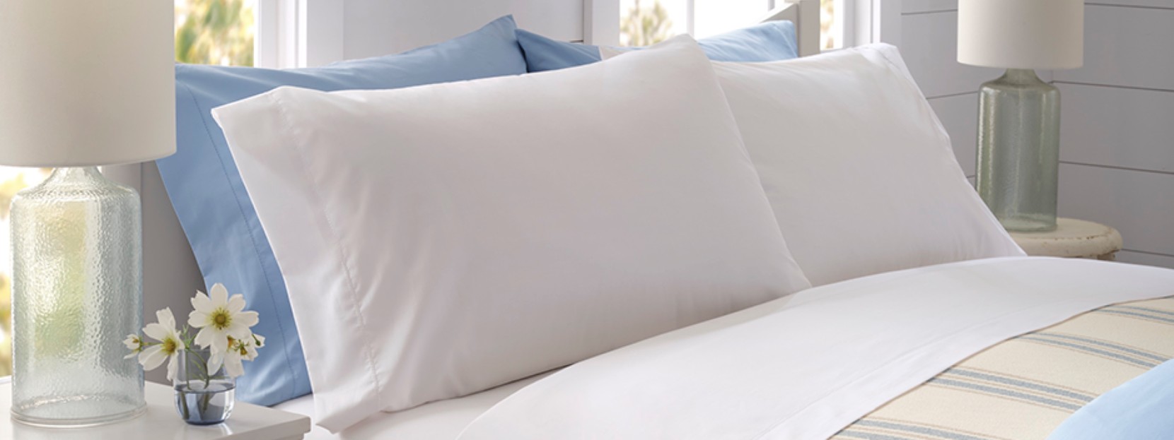 A neatly folded bed with plush, white pillows awaits a tired person.