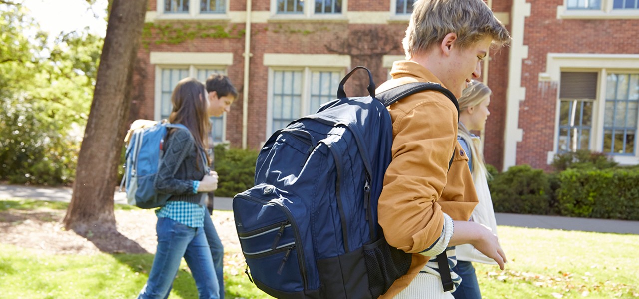 Several teens walking on school campus wearing L. L. Bean backpacks.