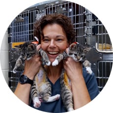 A smiling Rose Vincent holding 2 kittens up to her face.