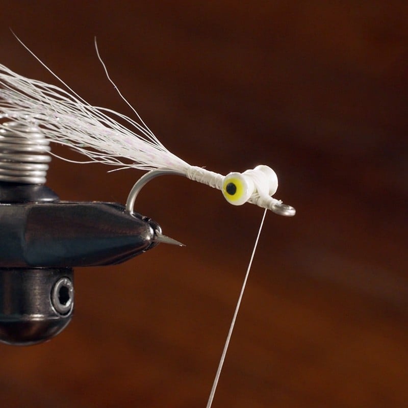 White synthetic fibers tied to a fishing hook.