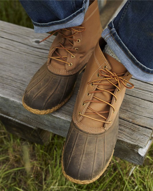 A close-up from above of Bean Boots worn by someone with their feet on a weathered wooden board.