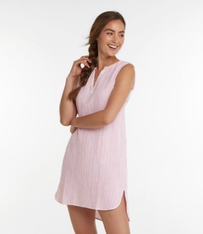Person in pink striped sleeveless cover-up dress with braid, standing against plain background.
