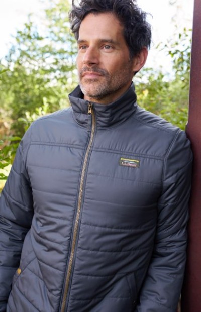 A person in a dark gray quilted jacket with a high collar and zip front, featuring an L.L.Bean logo patch on the chest.