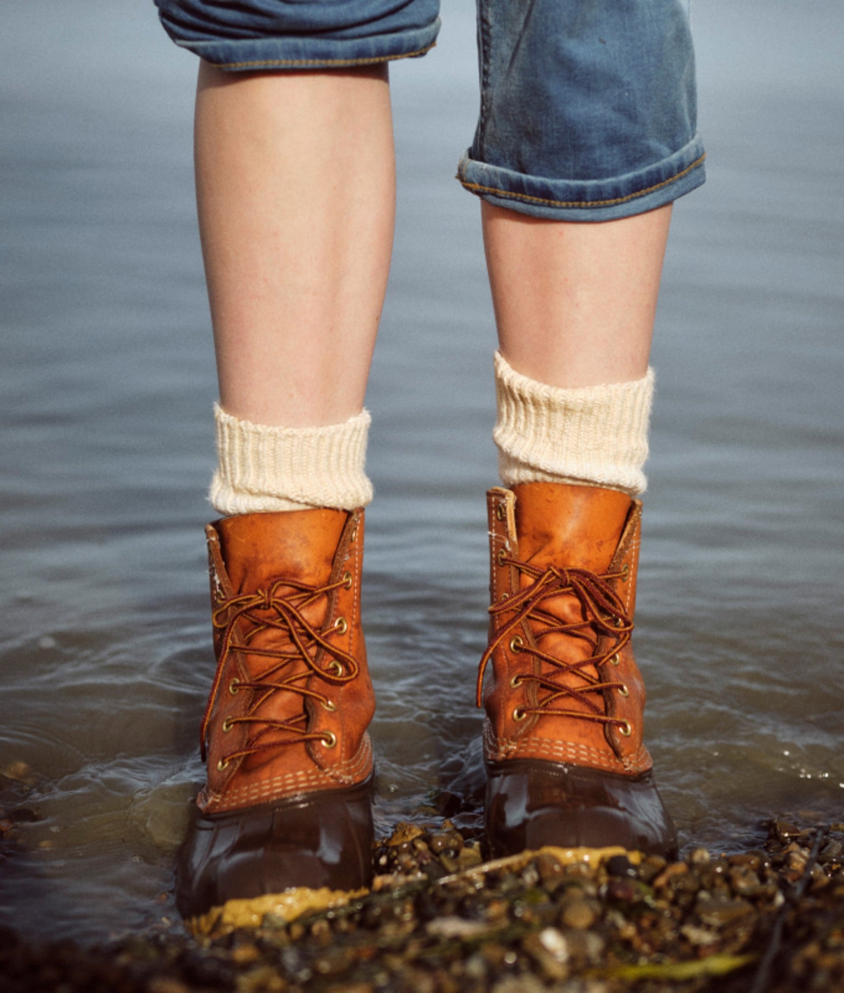 L L Bean boots worn in shallow water along a rocky shoreline.
