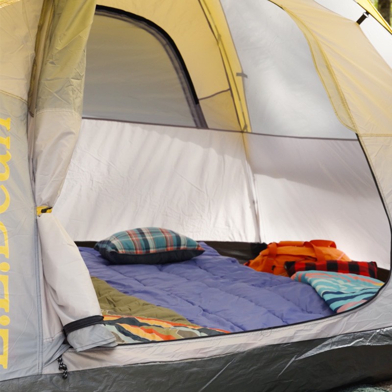 The interior of a cozy L L Bean tent with a sleeping bag and pillows.