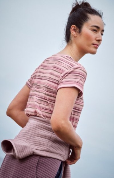 Person wearing a pink striped top, viewed from the side against a light background.