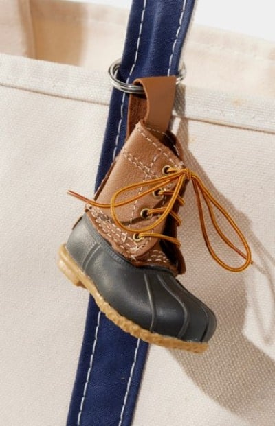 Miniature L. L. Bean Boot keychain attached to a blue tote strap.