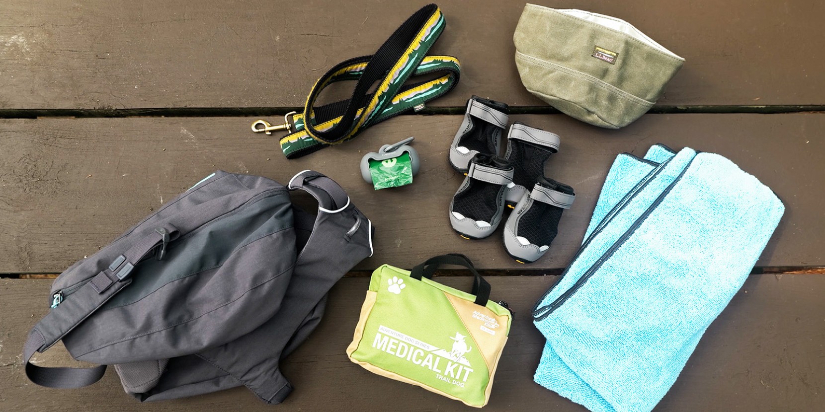 A green and black strap, a gray pouch, and a blue towel are placed on a wooden surface.