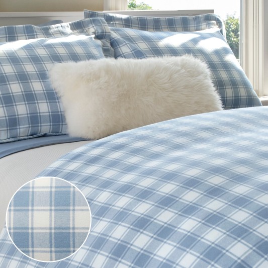 A neatly folded bed with blue plaid sheets along with an inset showing pattern details.