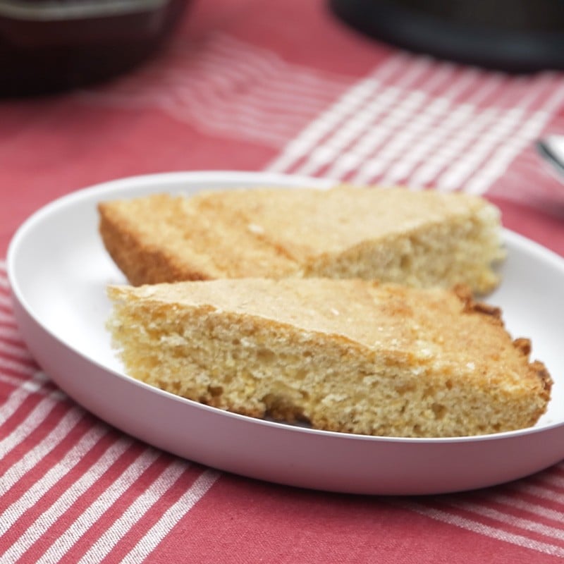 A plate of cornbread on a white plate, placed on a red and white striped cloth.