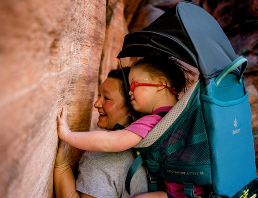 Melody Forsyth and daugther Ruby touching a rock wall on a hike.