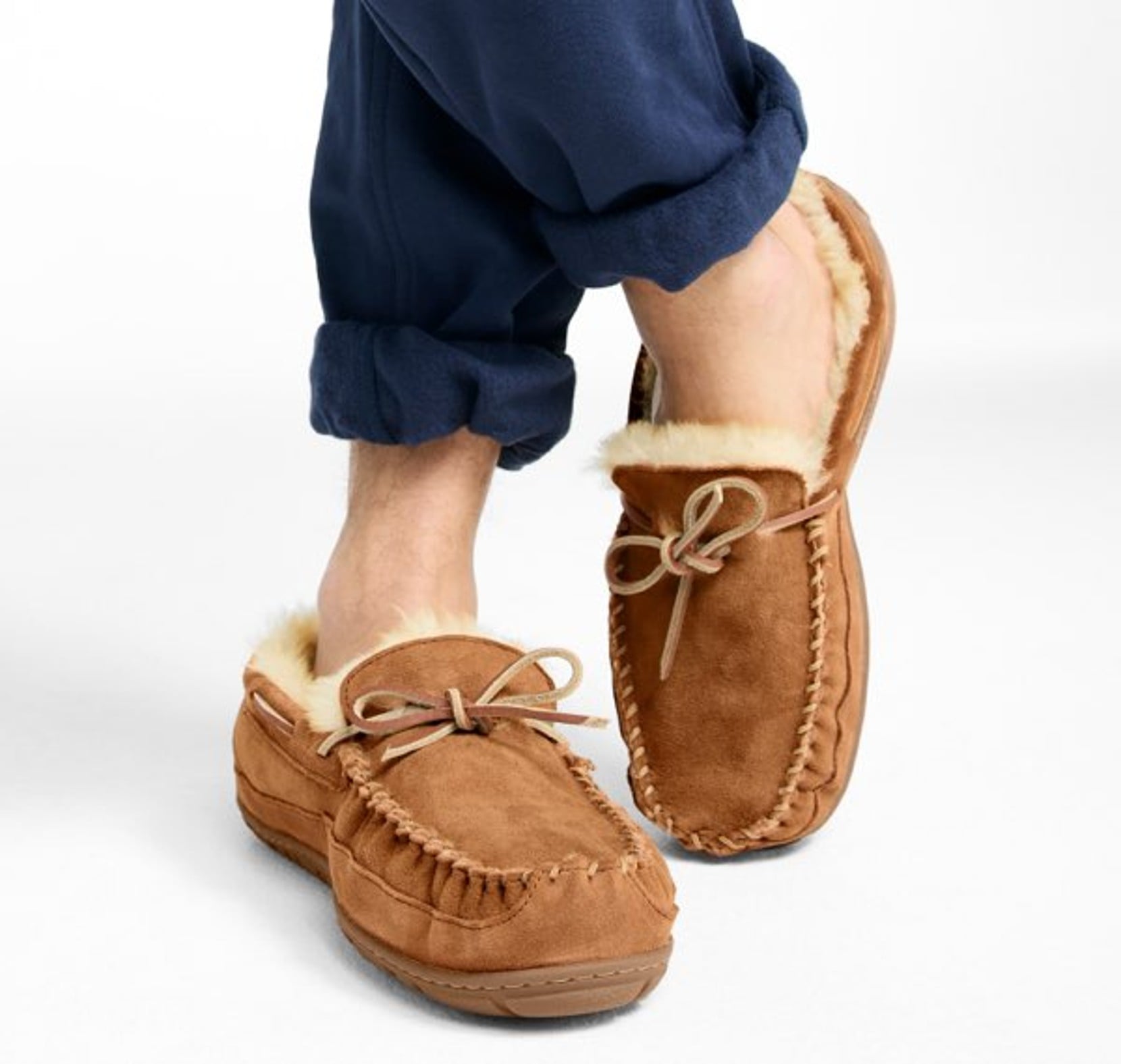 Person wearing brown shearling-lined moccasin slippers with cuffed sweat pants.