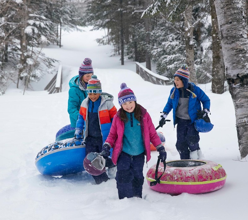 4 kids climbing a sledding hill.