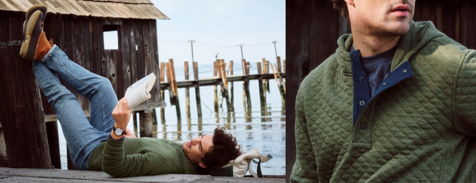 Person in a green quilted sweater relaxes on a dock reading, with weathered boathouses and piers over calm water.
