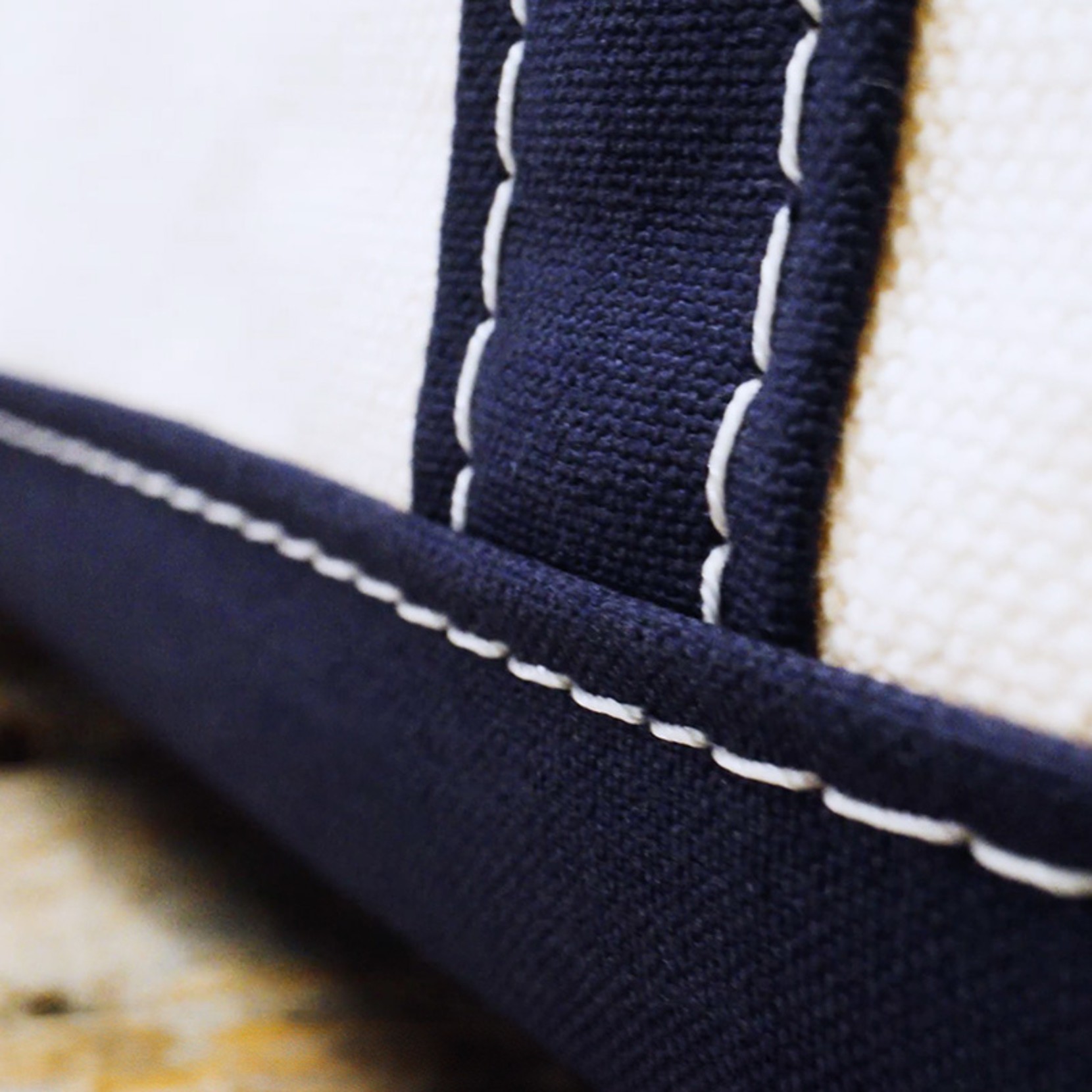 Close-up of navy blue and white fabric with detailed heavy duty stitching.