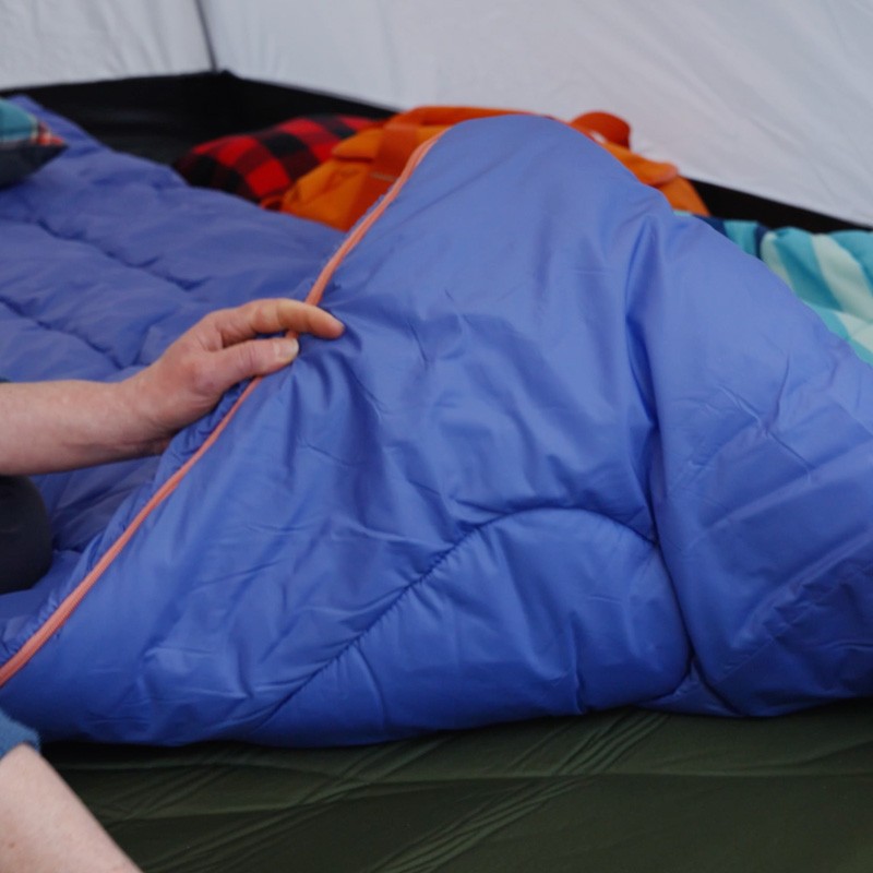 A person inspects a L L Bean sleeping bag in a tent.