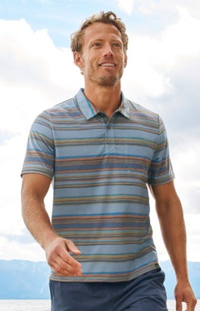Person wearing a blue and gray striped polo shirt paired with dark shorts, set against a bright outdoor background.