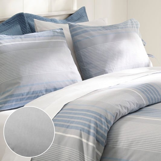 A neatly folded bed with gray sheets along with an inset showing cotton details.