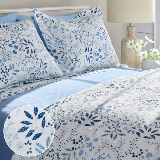 A neatly folded bed with blue floral sheets along with an inset showing pattern details.