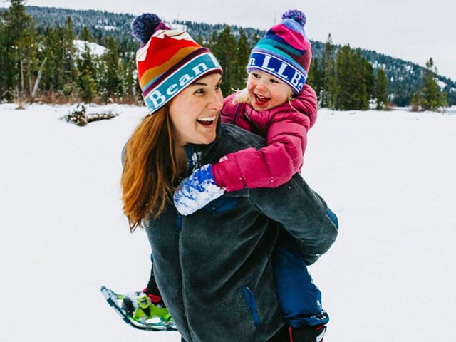 Madison Bowman carrying one of her children on her back outside in the snow.