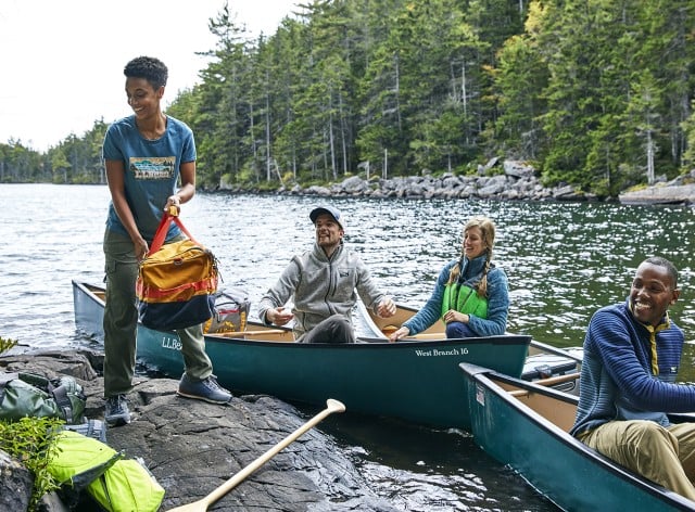 Group of people exiting canoe with camping supplies.